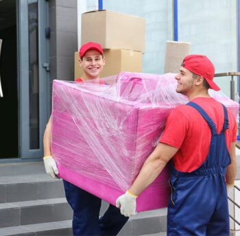 Umzug in Butzbach Zwei Umzugshelfer tragen ein in Folie gepacktes Möbelstück – Umzug in Butzbach