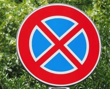Rundes Halteverbotsschild vor grünem Laub – Stellplatz für den Umzugswagen